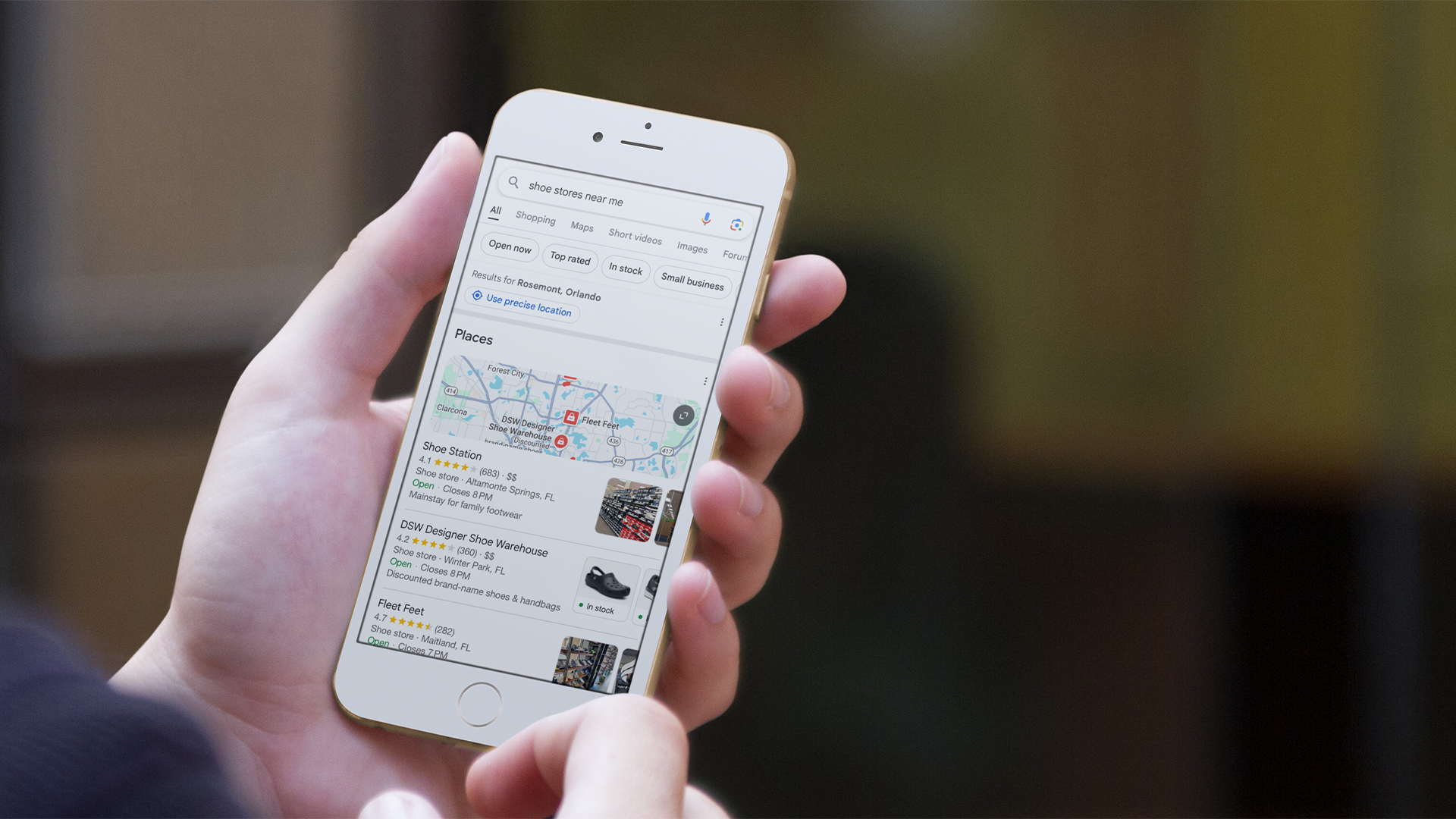 person holding phone searching up closet shoe stores near me on google